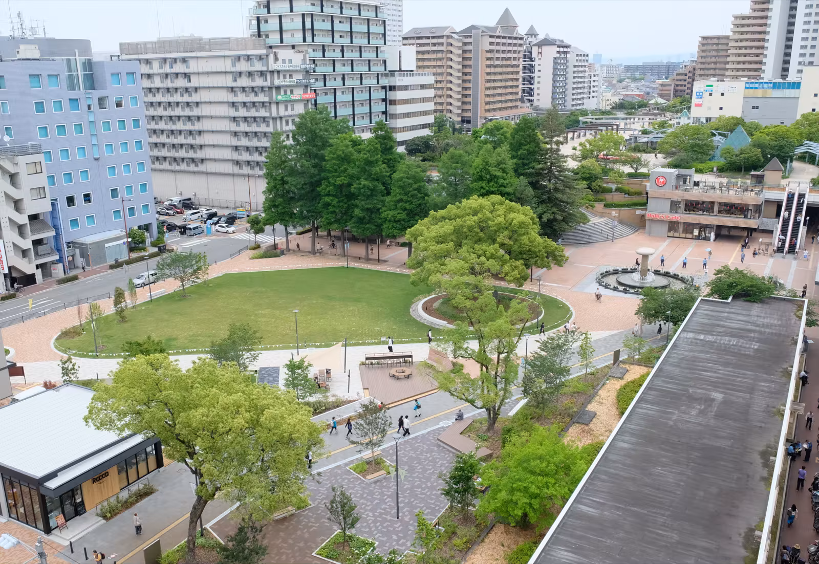 阪神尼崎駅前・中央公園の鳥瞰パース。芝生の広場と噴水、周囲のビル群