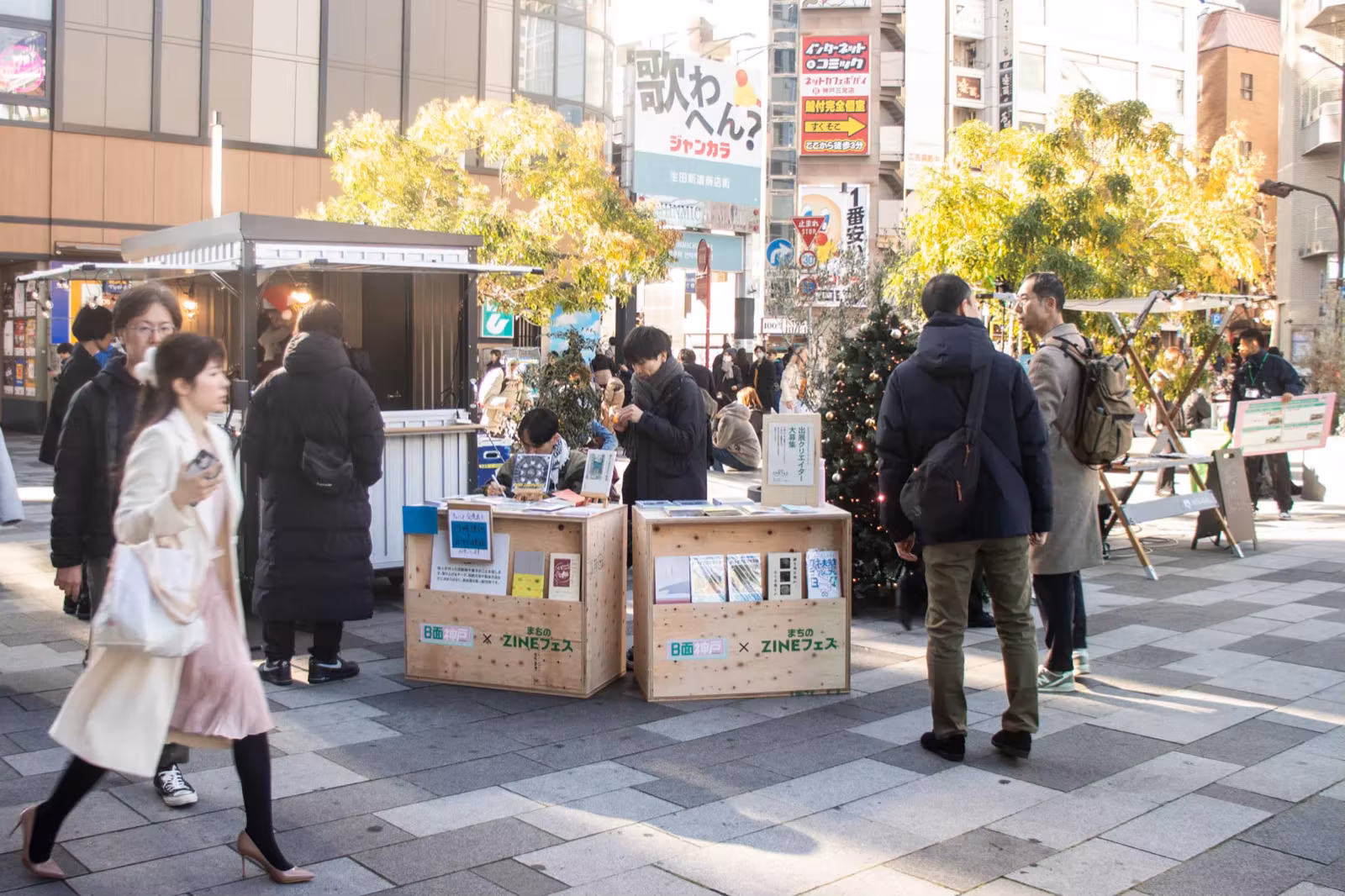 駅前の広場に並んだ屋外マーケットのブースと、立ち寄る来場者