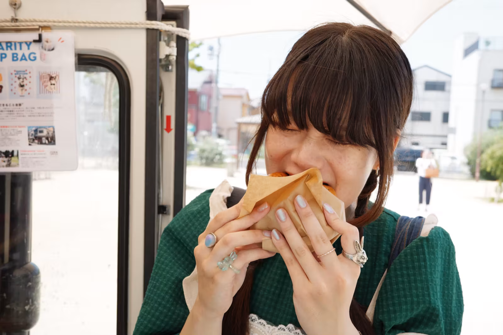 キッチンカーの前で、紙袋に入ったフードをほおばる女性