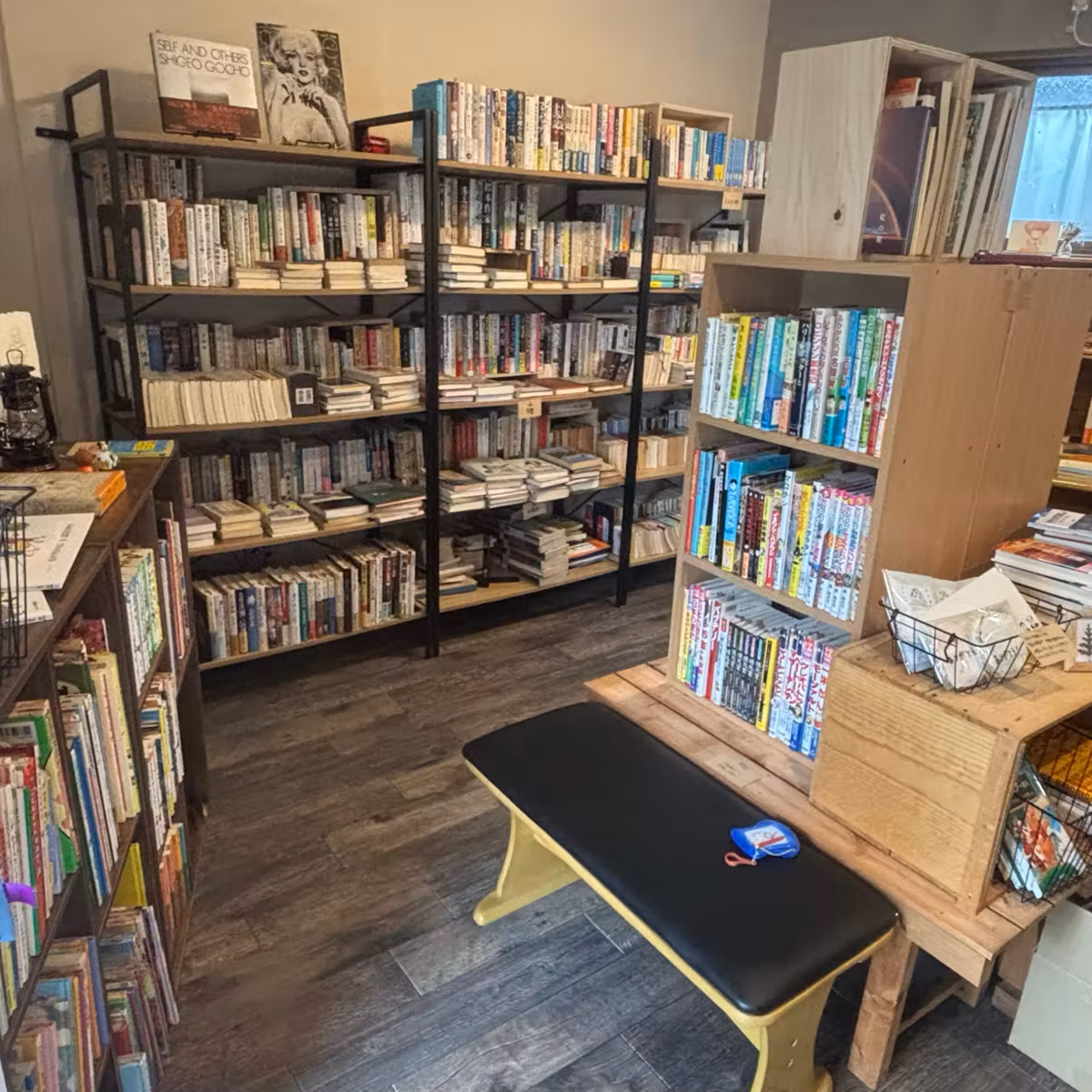 スチールラックの本棚に囲まれた部屋。中央に木のベンチ
