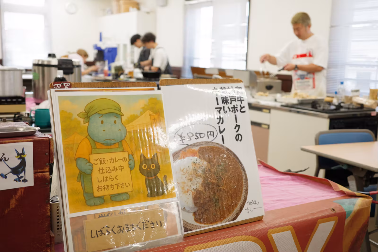 過去開催のフードブース。カレーのメニュー看板の奥でスタッフが調理している