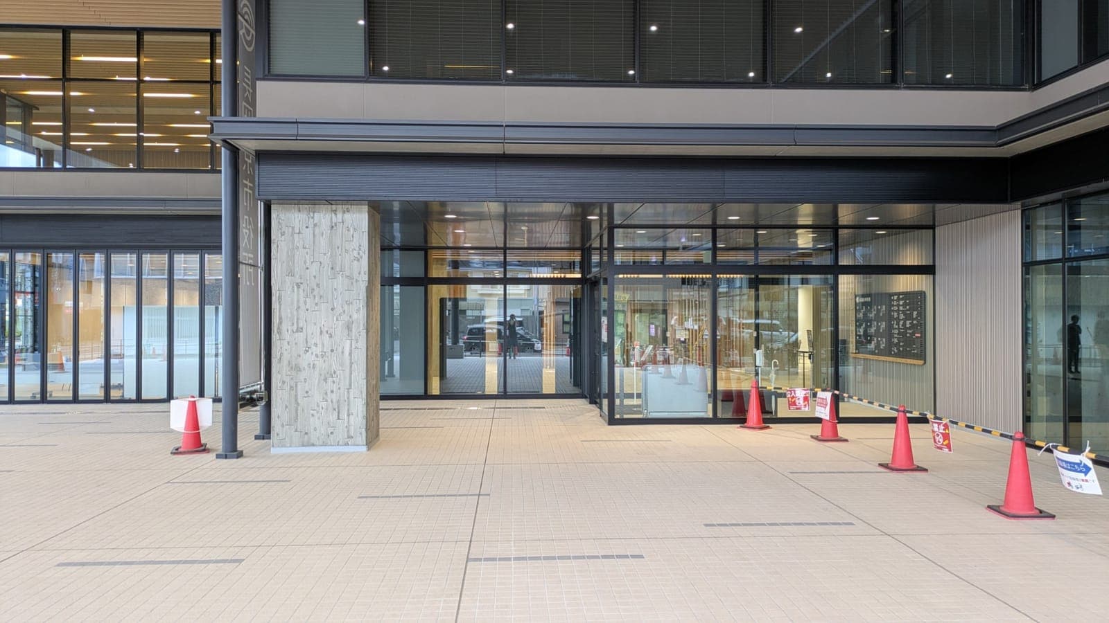 長岡京市役所の1階エントランス。ガラス張りの出入口と木目調の柱、タイル敷きの広場