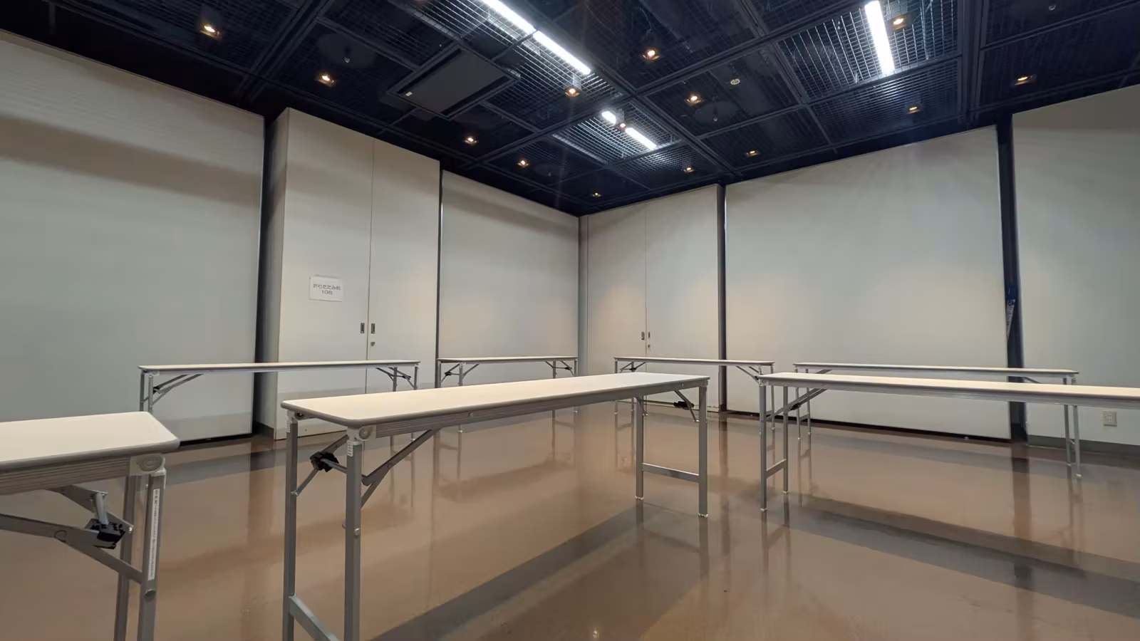 長岡京市中央生涯学習センターの会場内観。白い壁の部屋に長机が並んでいる